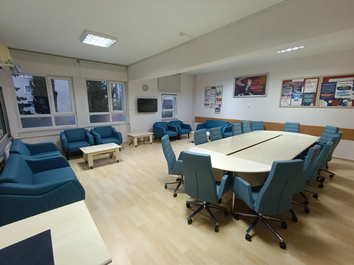 İstanbul Ofis Mobilya tarafından yenilenmiş, mavi koltuklu ve geniş toplantı masalı modern öğretmenler odası tasarımı.