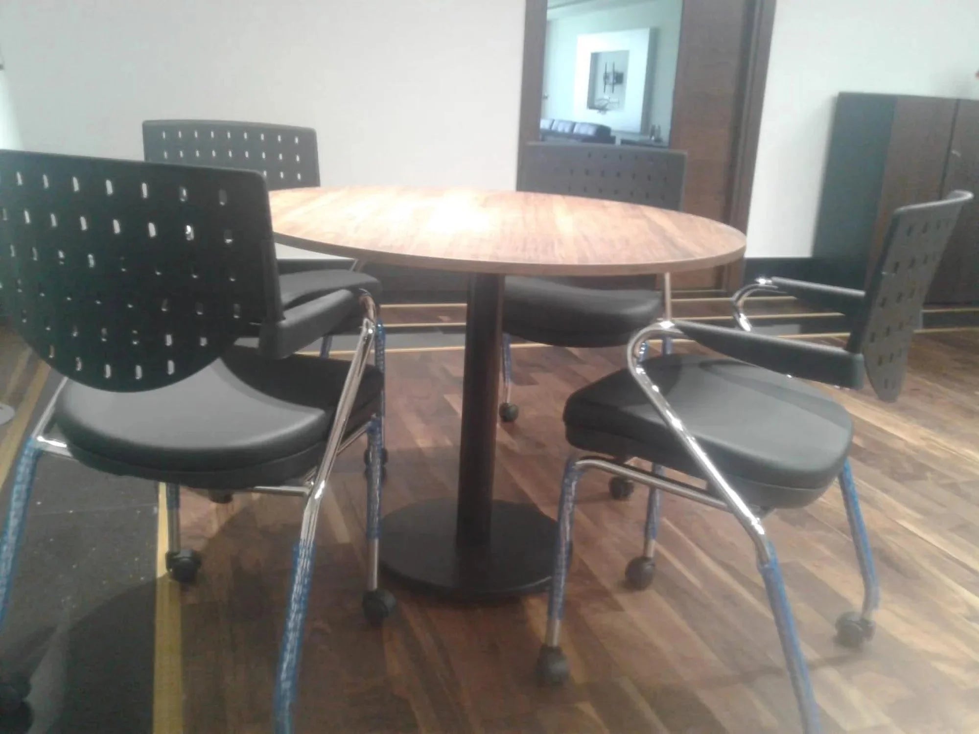 İstanbul Ofis Mobilya ahşap tablalı yuvarlak toplantı masası ve dört adet siyah tekerlekli ofis sandalyesi seti.