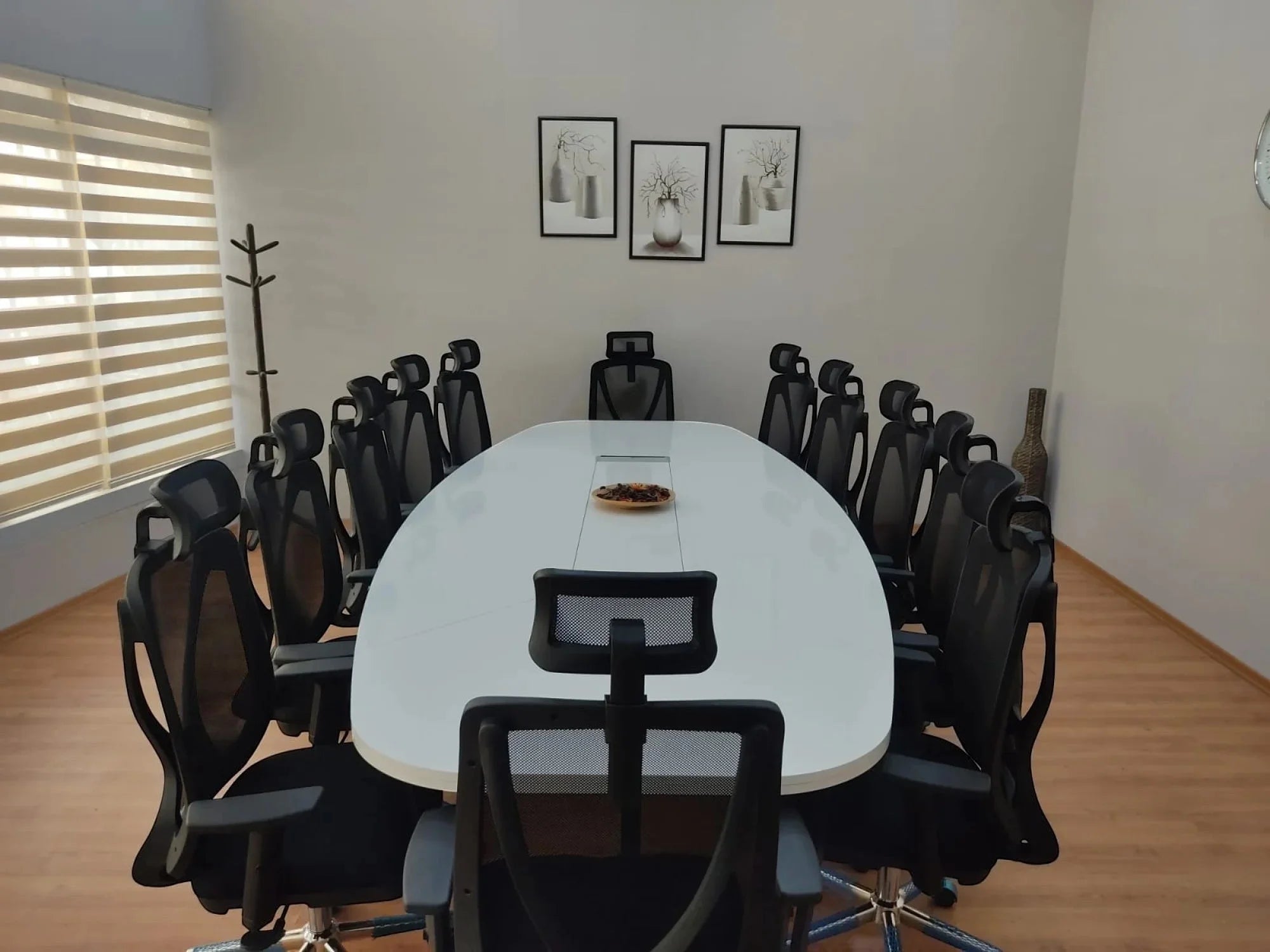 İstanbul Ofis Mobilya marka beyaz oval toplantı masası, siyah fileli ofis sandalyeleri ile modern toplantı odasında.